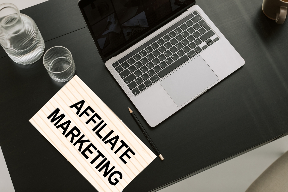 prikaz laptopa, čaše sa vodom, čaša sa vodom i papira na kom piše affiliate marketing
